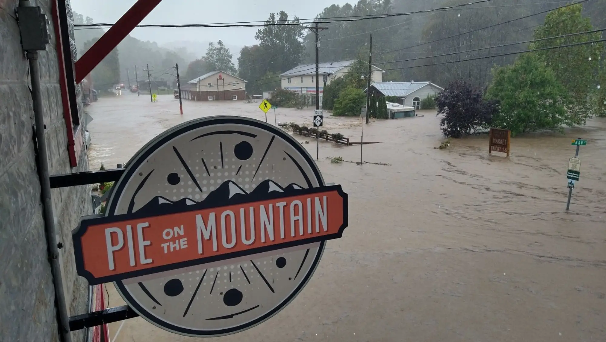 The Pie on the Mountain sign above a flooded downtown Lansing street during Hurricane Helene